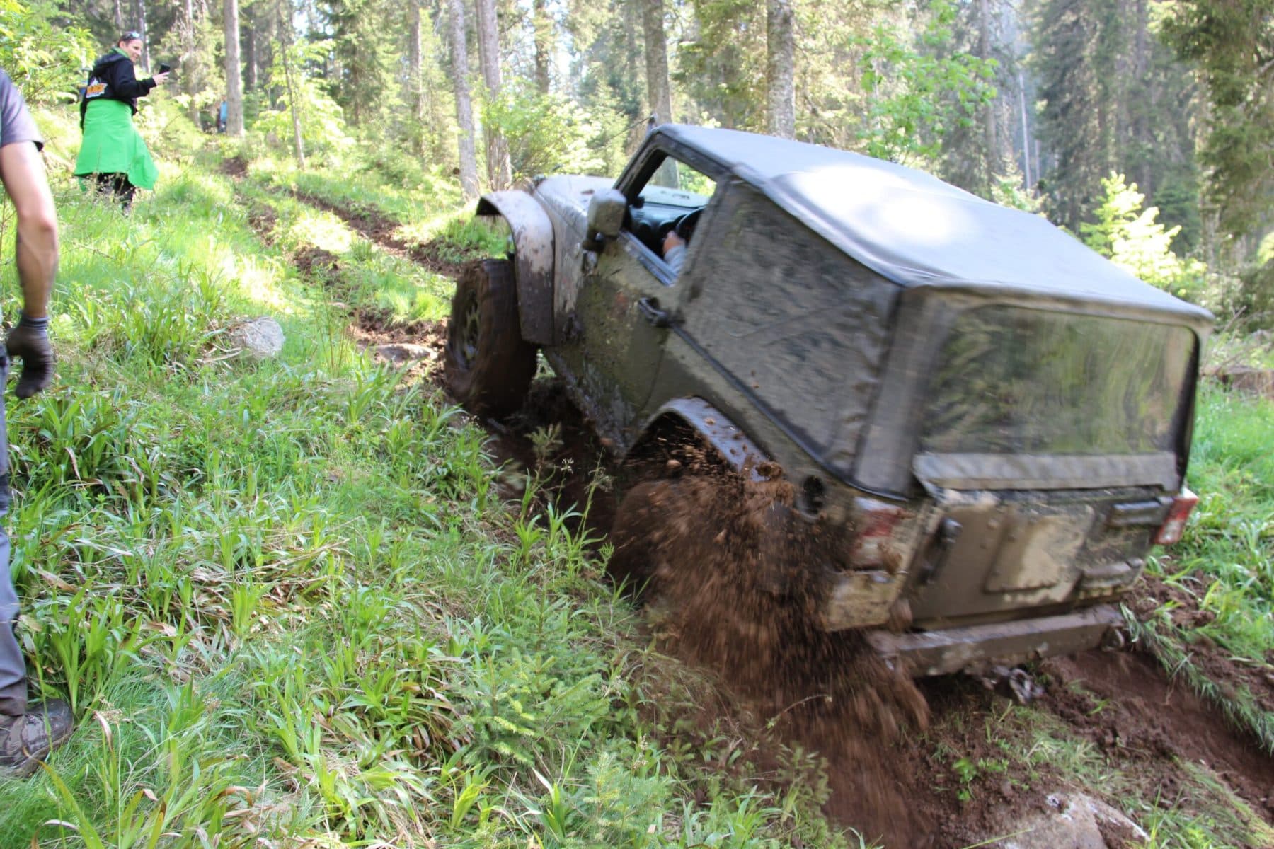 Ein Geländewagen erklimmt eine schlammige Waldpassage